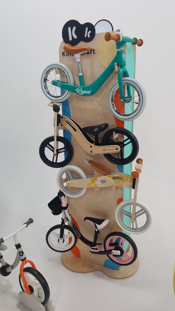 wysoki drewniany ekspozytor na którym są rowerki biegowe